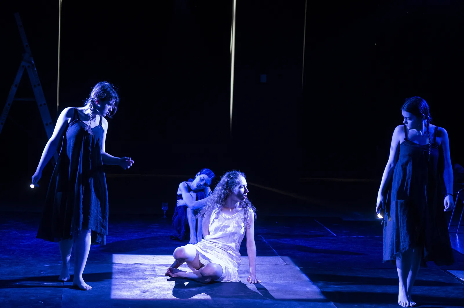 Eurydice seated in a shaft of white light with the Stones around her.