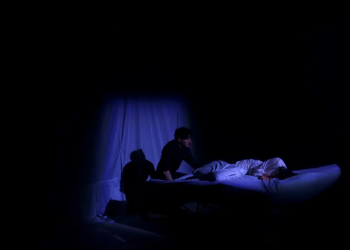 A figure leaning over the Duchess's bed in near darkness.