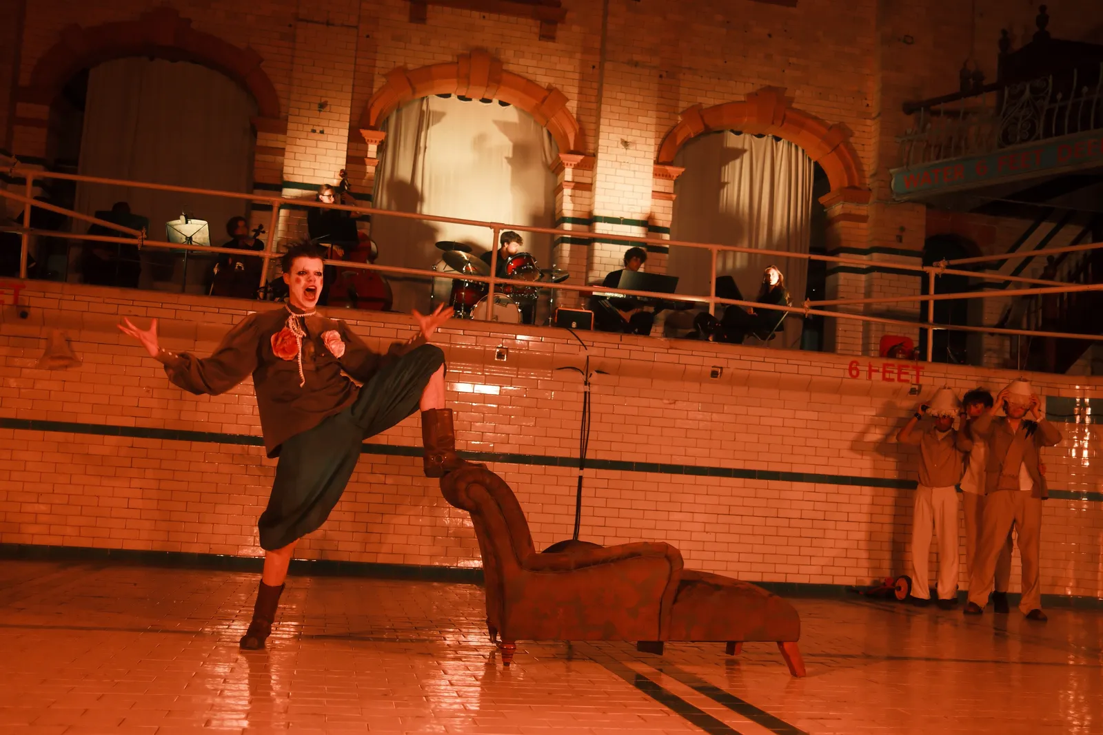 Existing Shakespeare production image: Queen Margaret screaming with the ensemble looking on from the tiled wall.